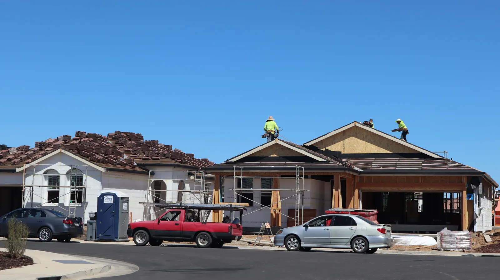 A house being re-roofed, seen from the street, with workers along the roof slope.