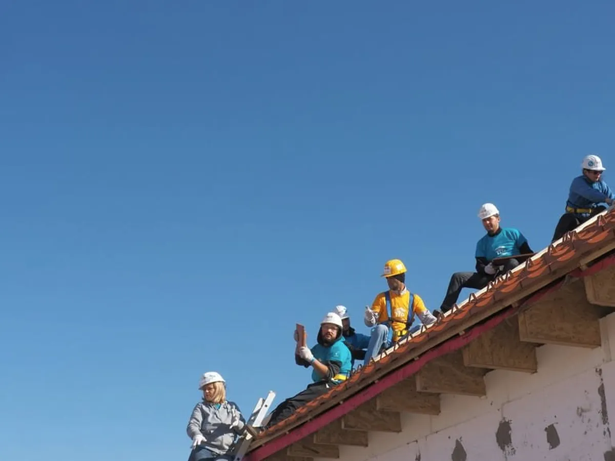 A crew in helmets along a roof edge.