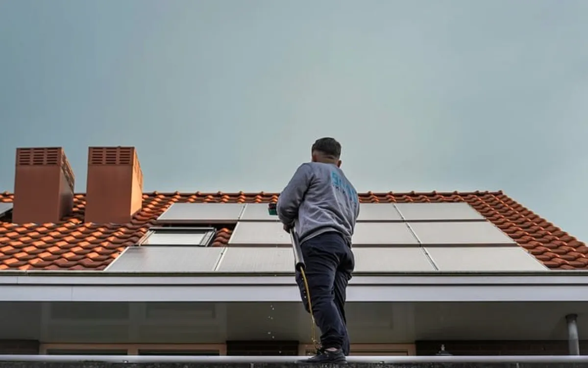 A roofer on a red tiled roof with chimneys.