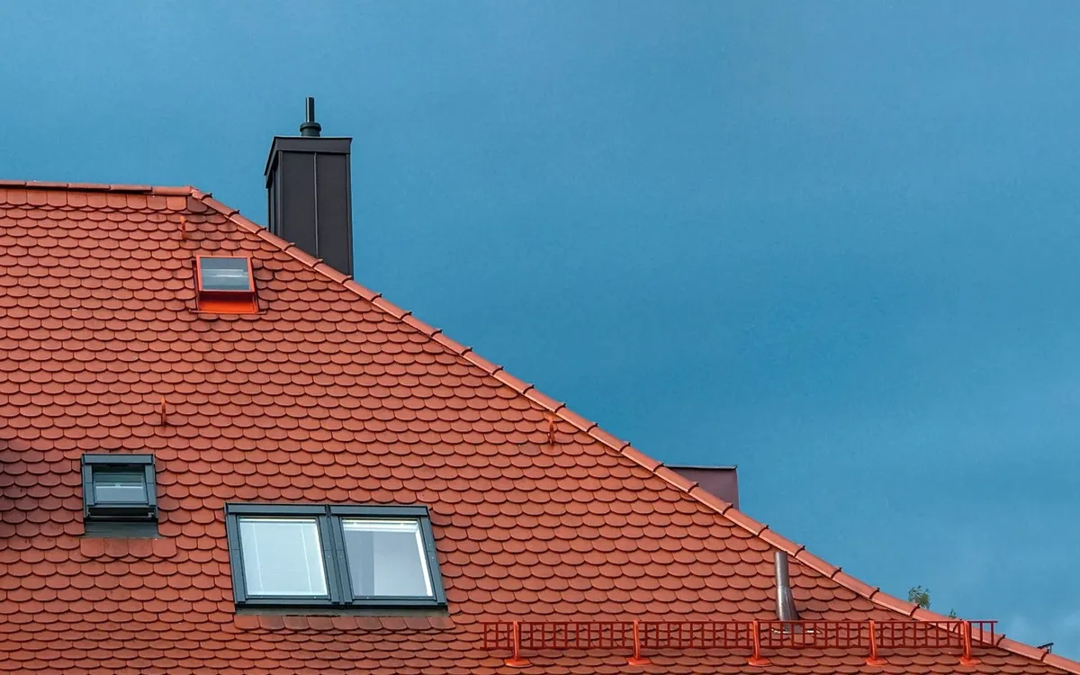 A red tiled roof with skylights against blue sky.