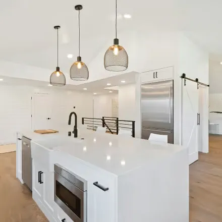 A white kitchen with a large island and pendant lights.