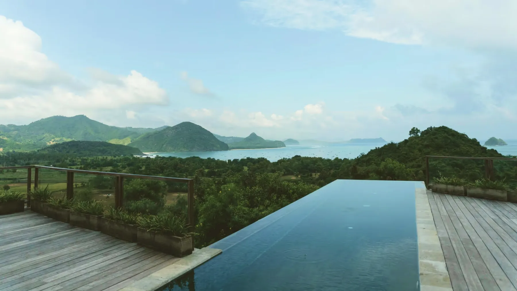 An infinity pool at dusk looking over green hills and the sea.
