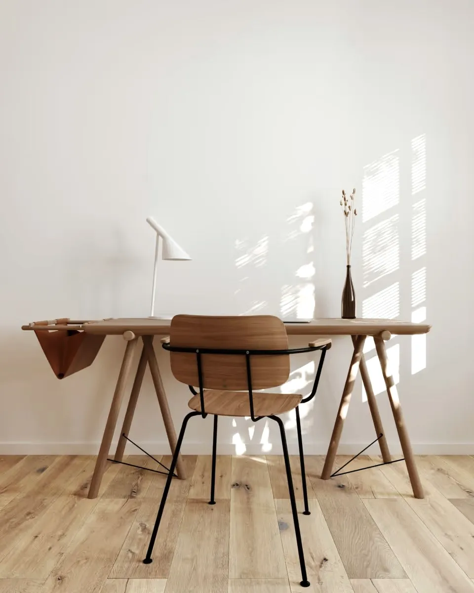 A wooden desk and chair with a white lamp and dried flowers.