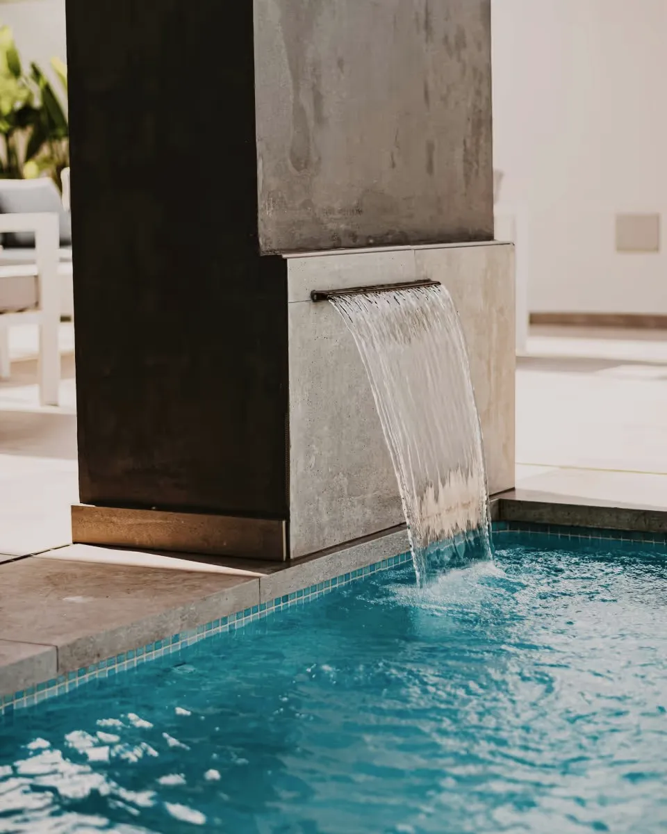 Water pouring from a stone spout into a blue pool.