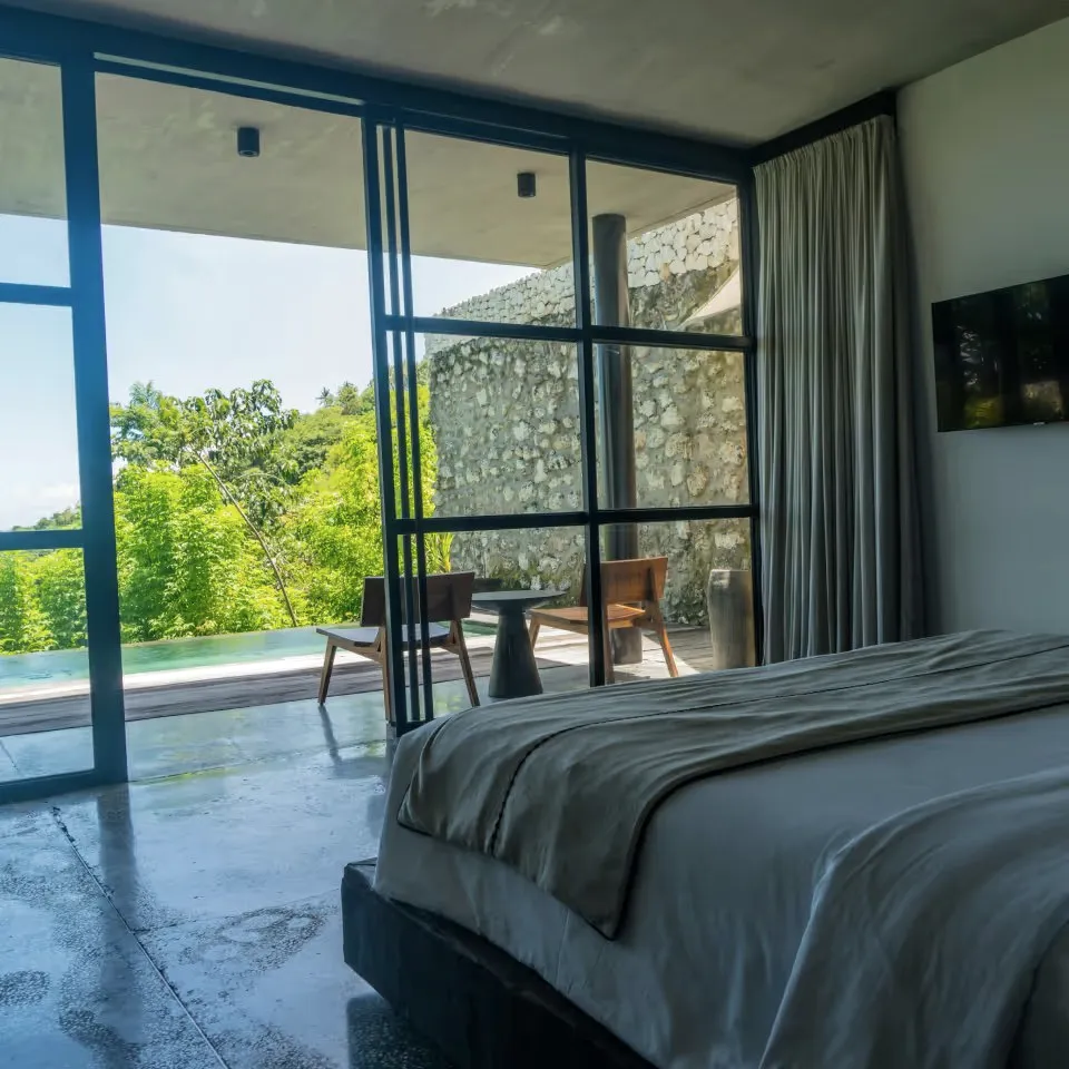 A bedroom with a wide bed facing glass doors onto a patio.