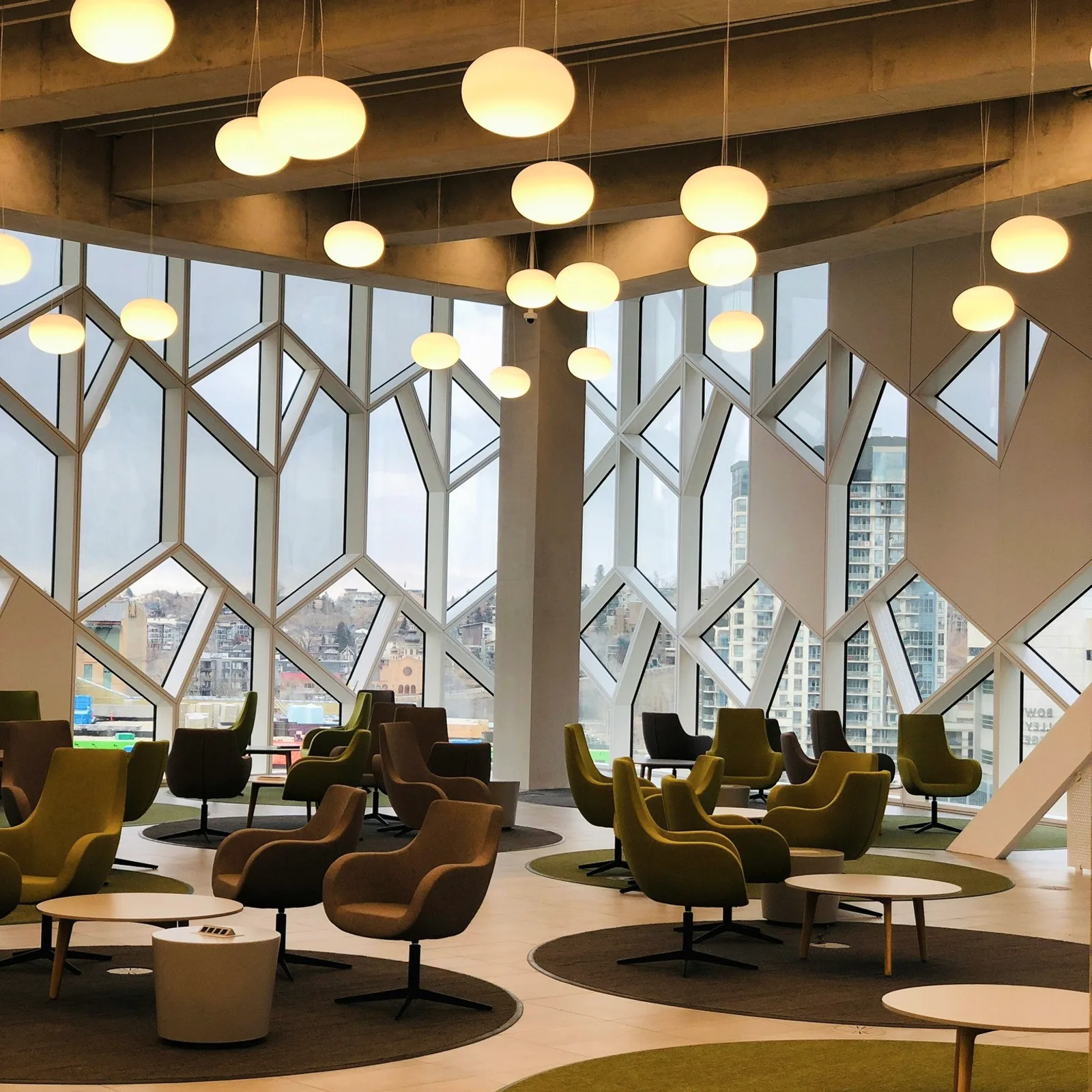 A lounge with round pendant lamps and geometric windows.
