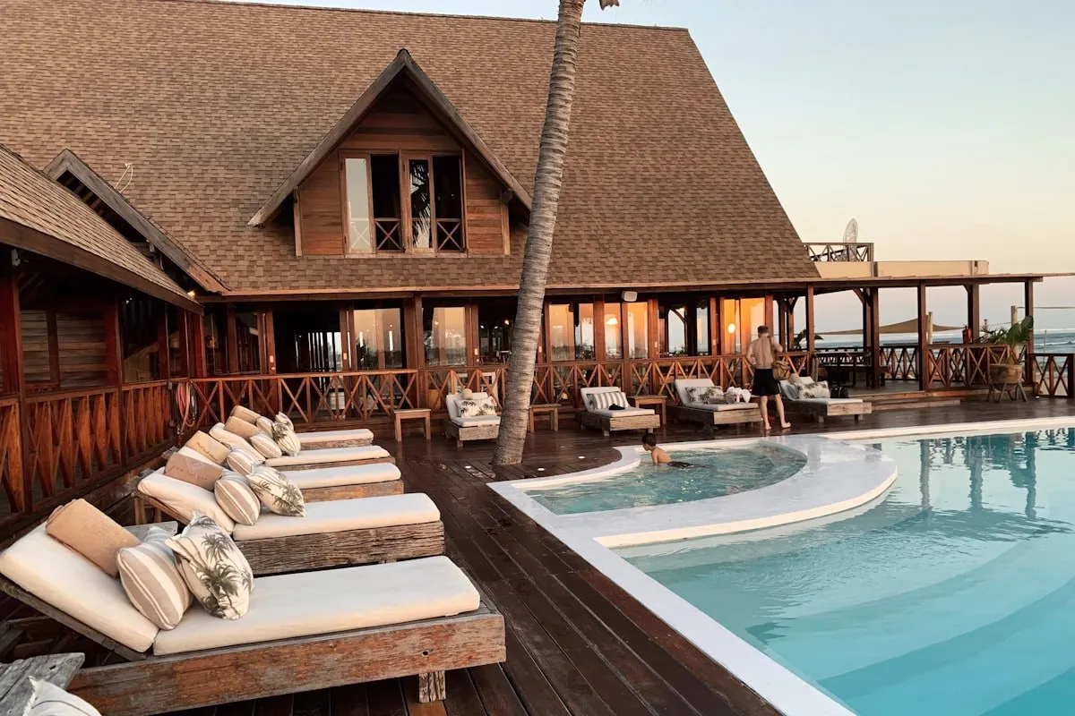 A pool deck with loungers at a wooden villa.