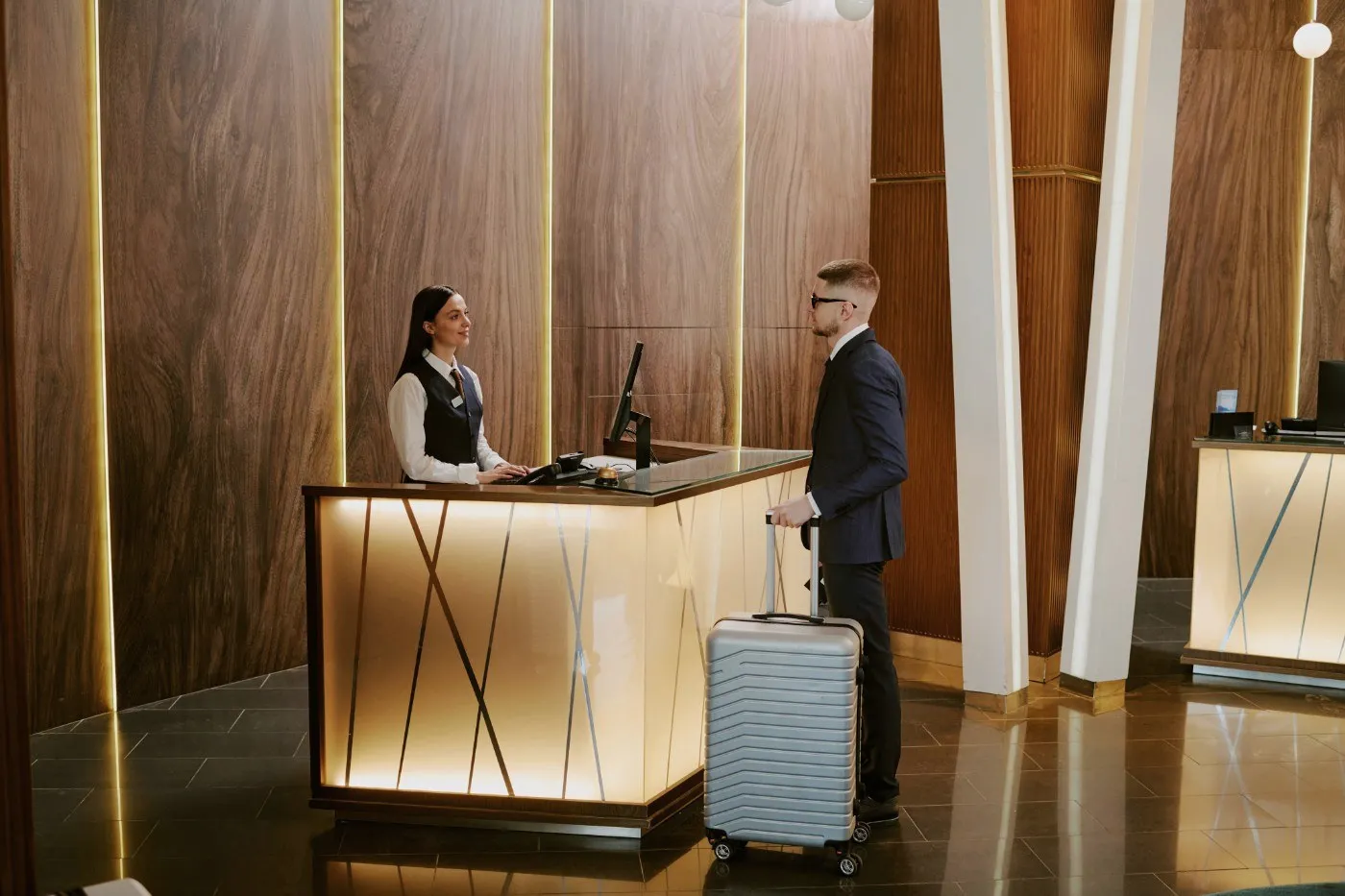 A guest at the reception desk, wood panelling behind.