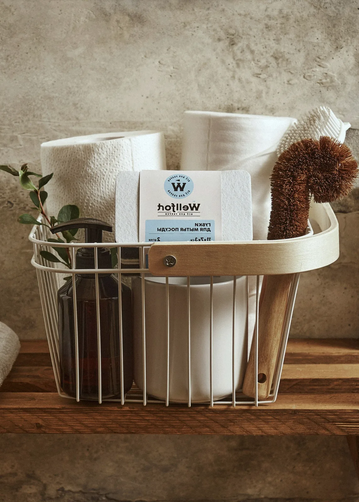 A basket of towels, a brush and a soap bottle.