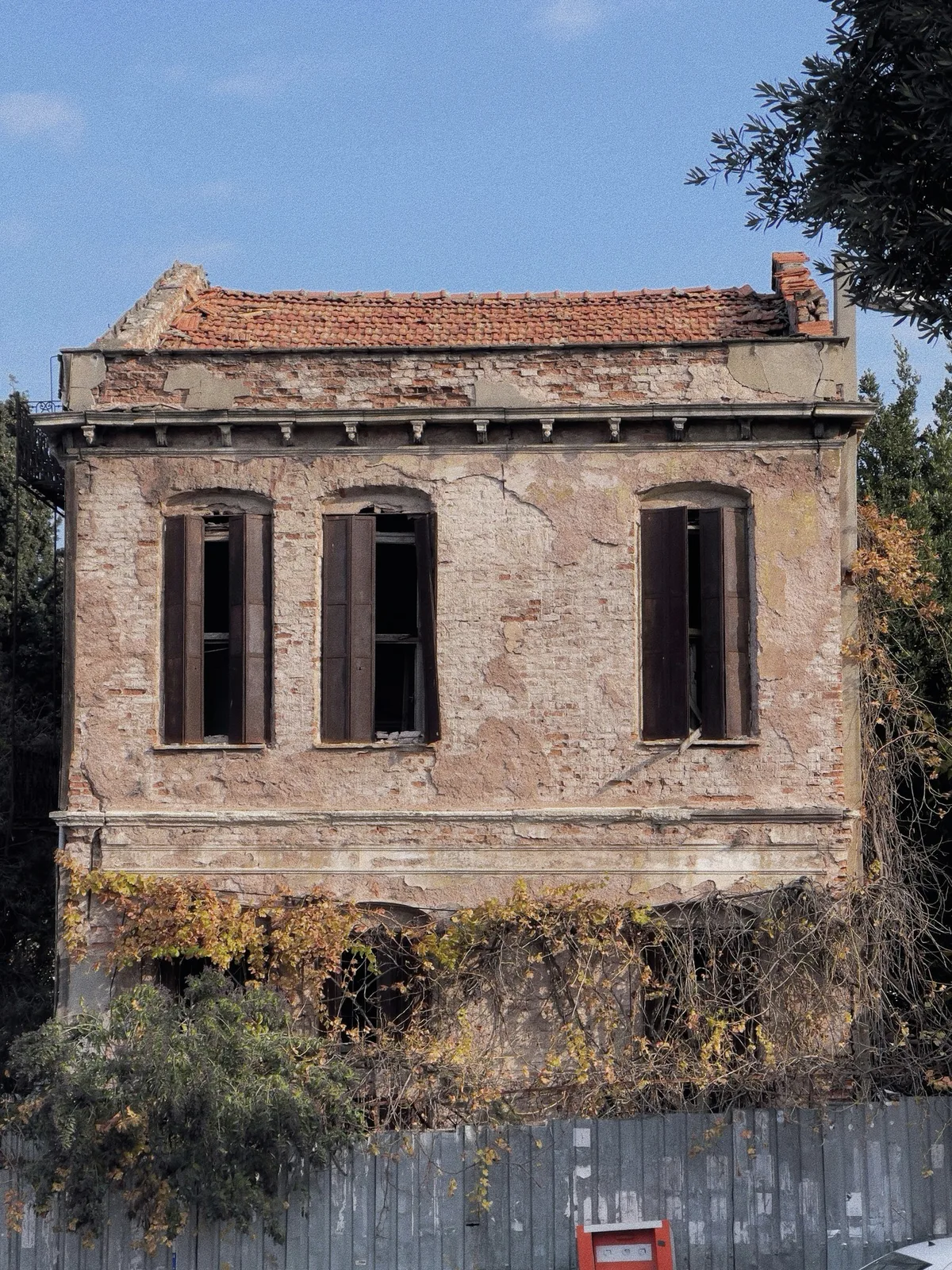 An old plastered facade with three shuttered windows.