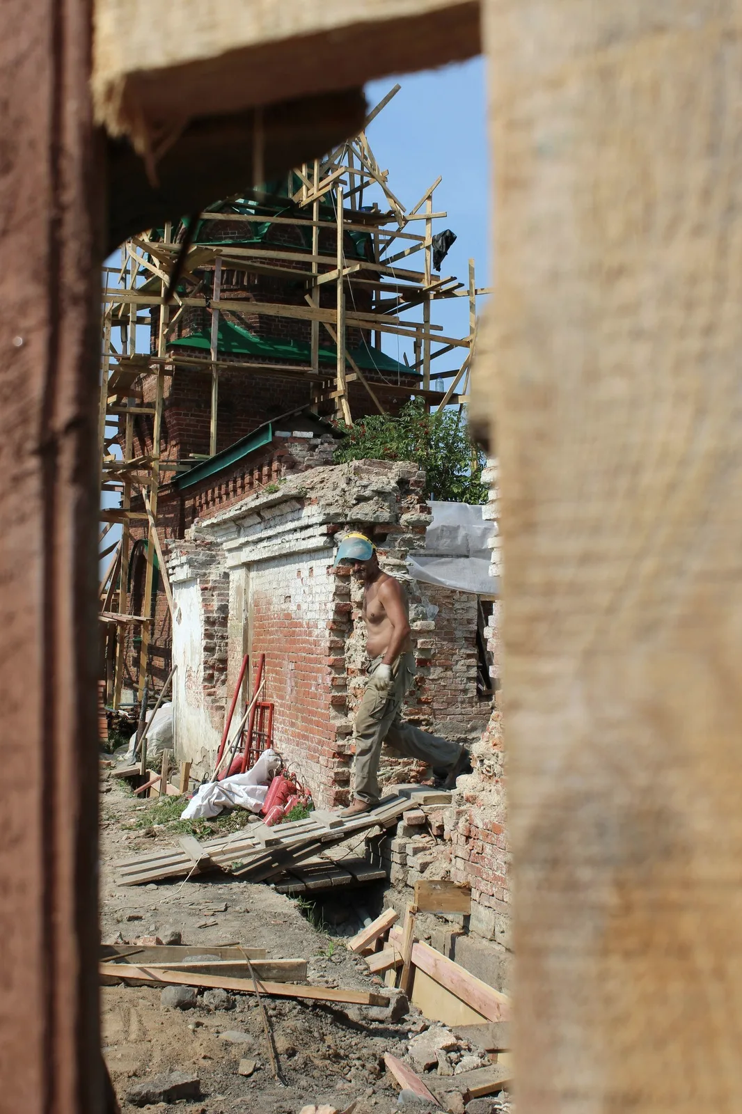 A worker on scaffolding at a brick wall.