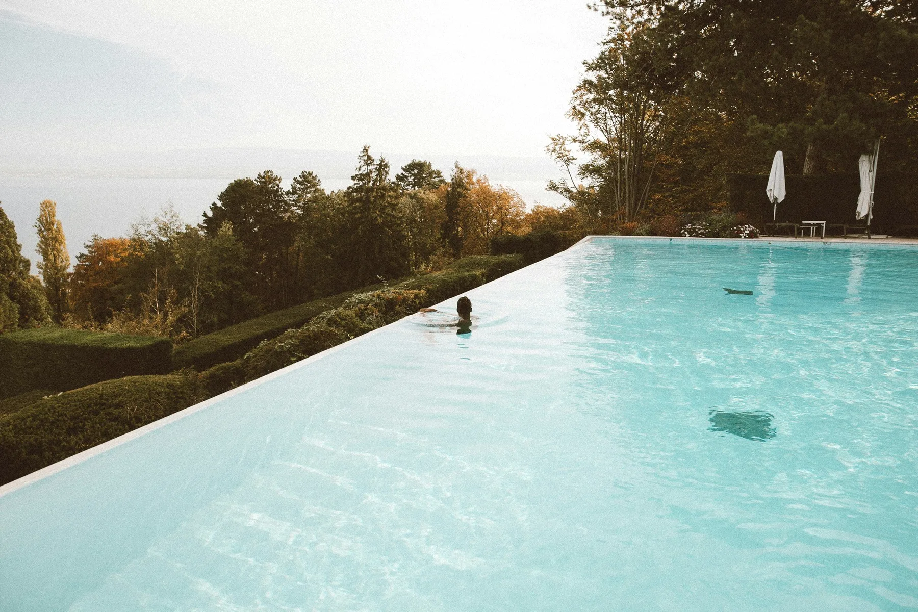 A swimmer in an infinity pool at the edge of a valley.