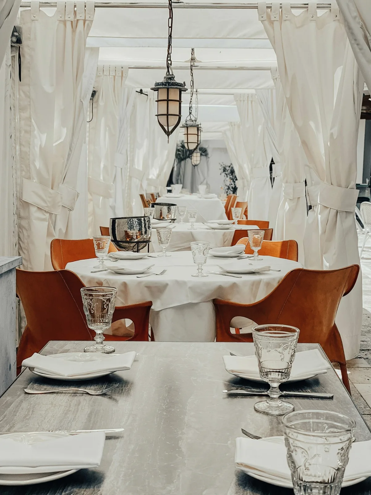 White tablecloths and leather chairs in a bright room.