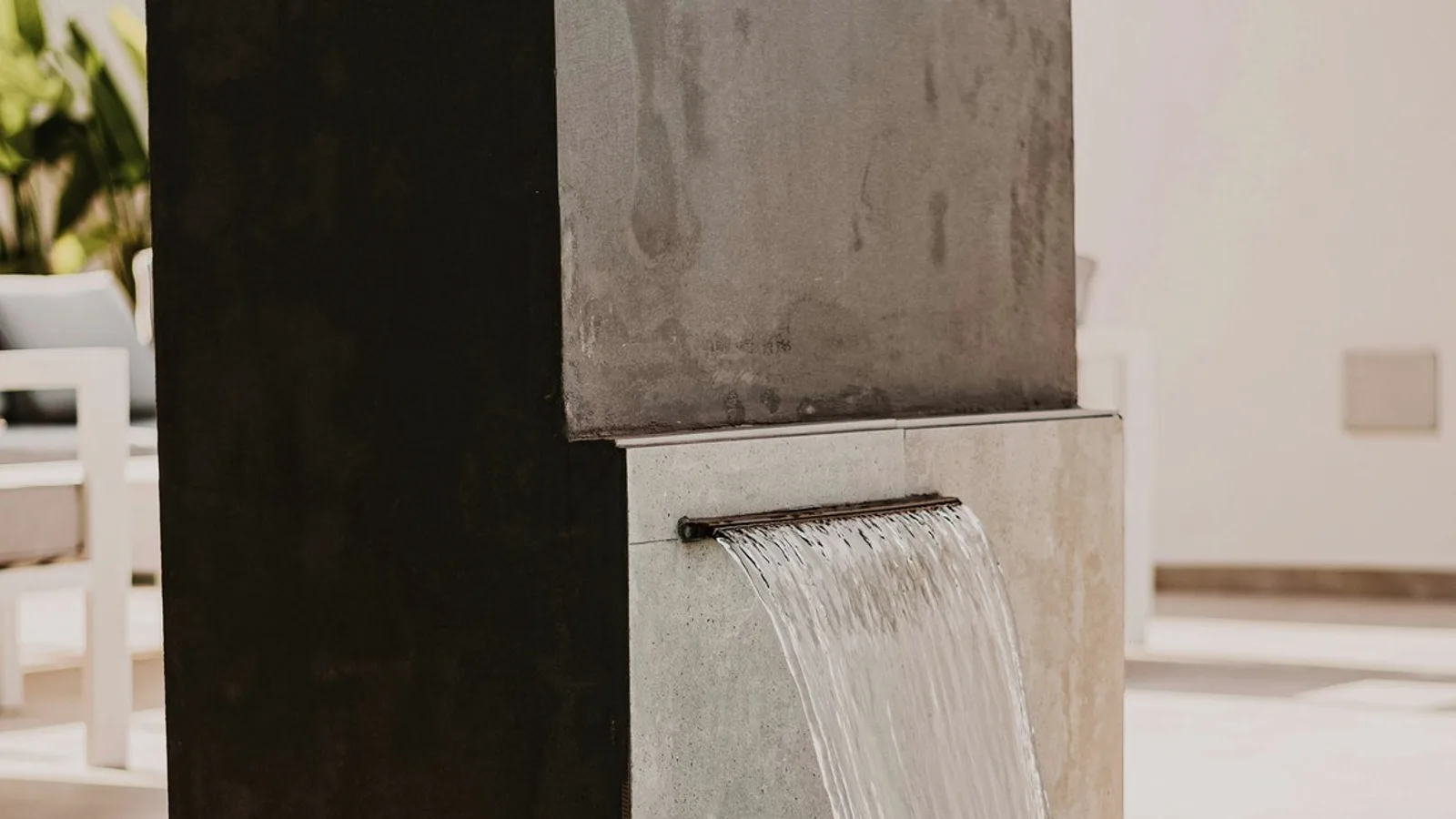 A sheet of water falling from a stone wall into a pool.