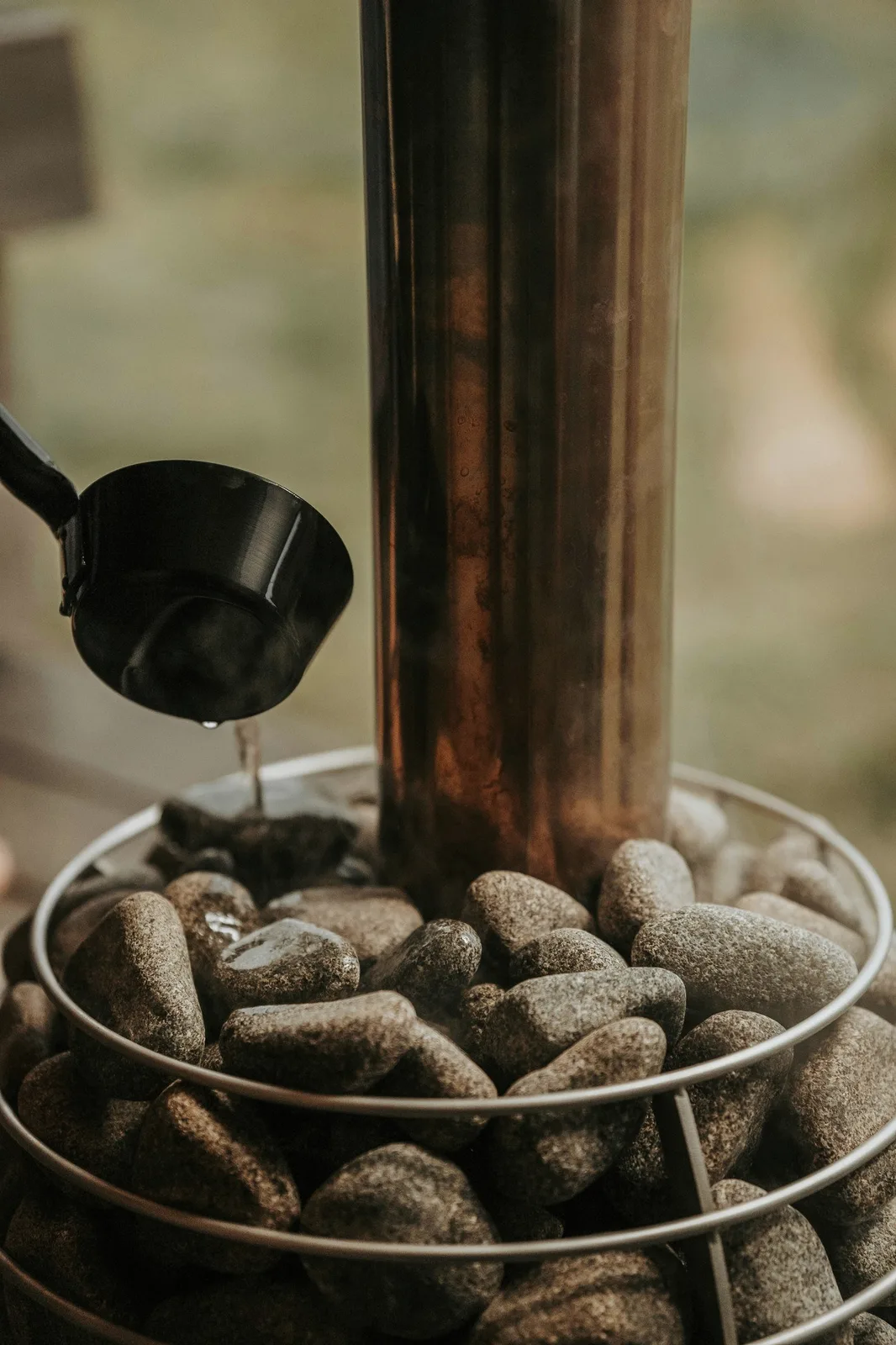Water poured from a ladle over hot stones.