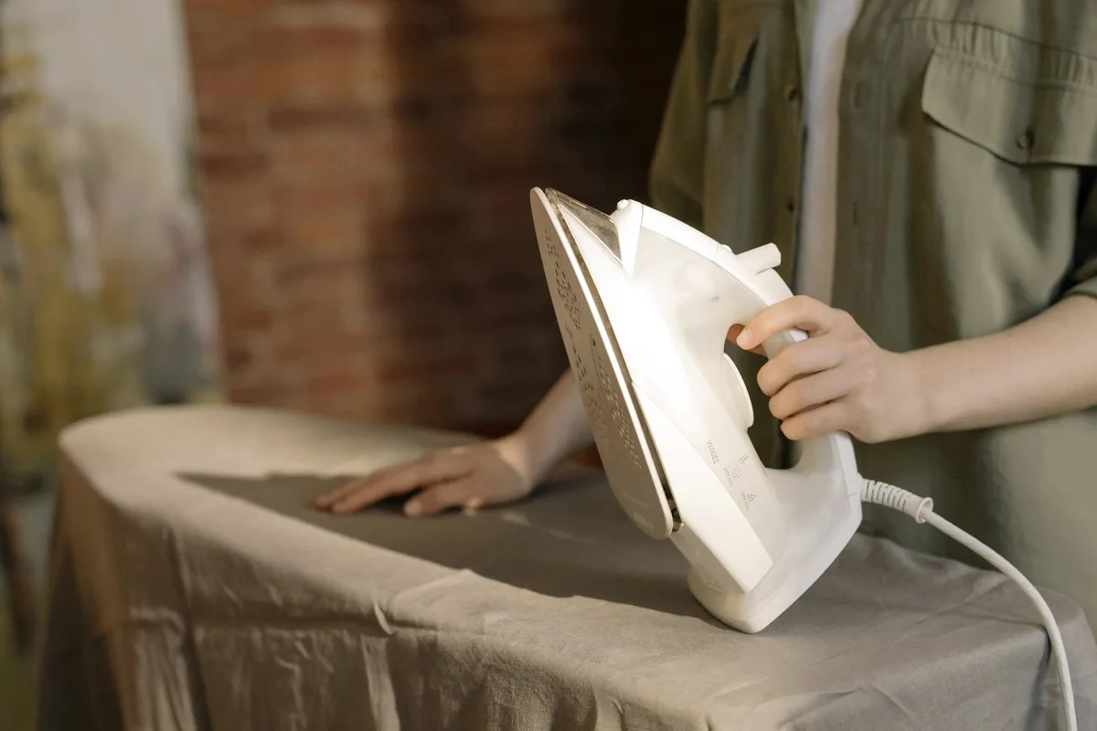 An iron on a shirt on an ironing board.