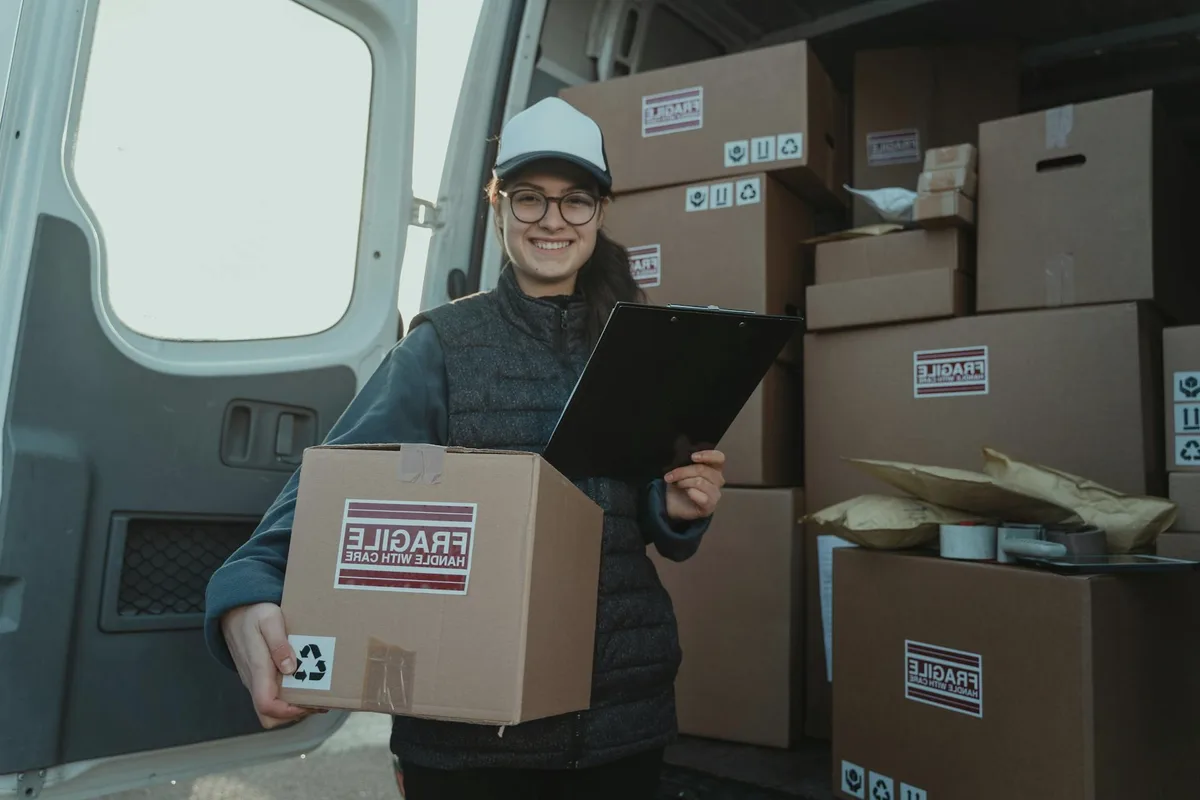 A courier with a parcel at a van door.