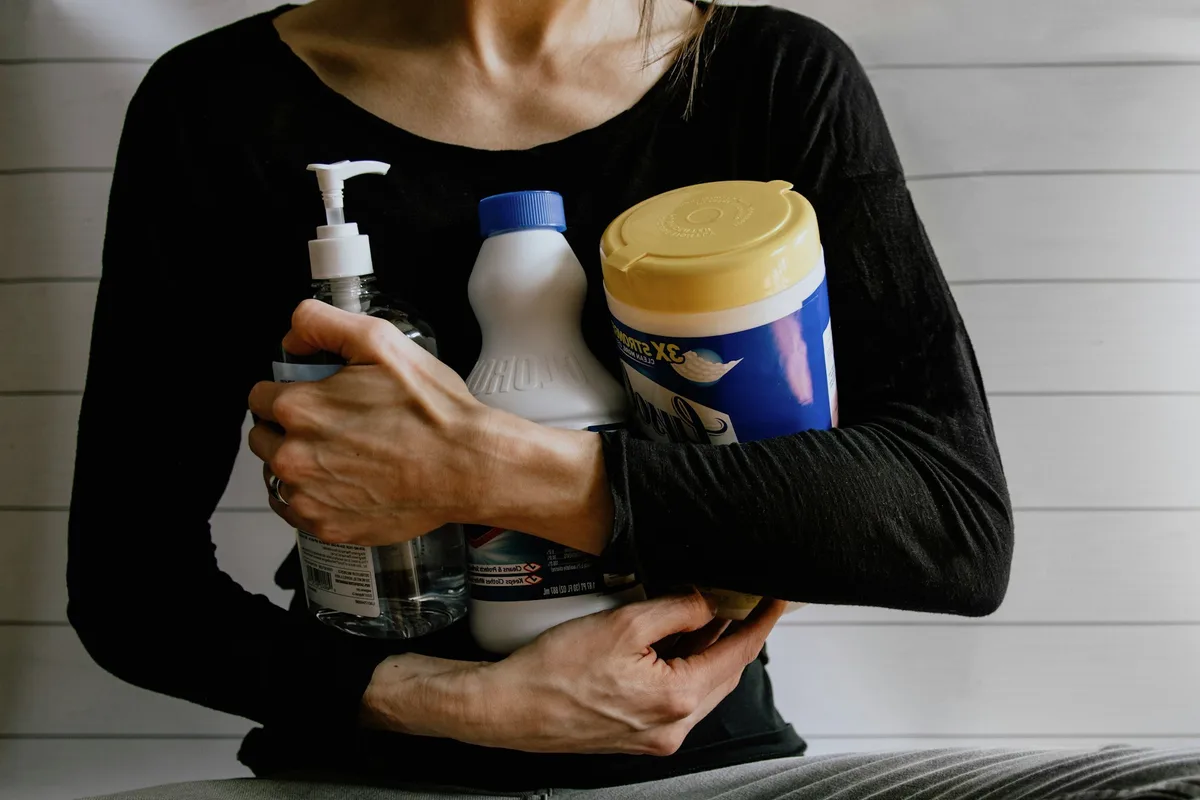 Arms holding cleaning bottles.