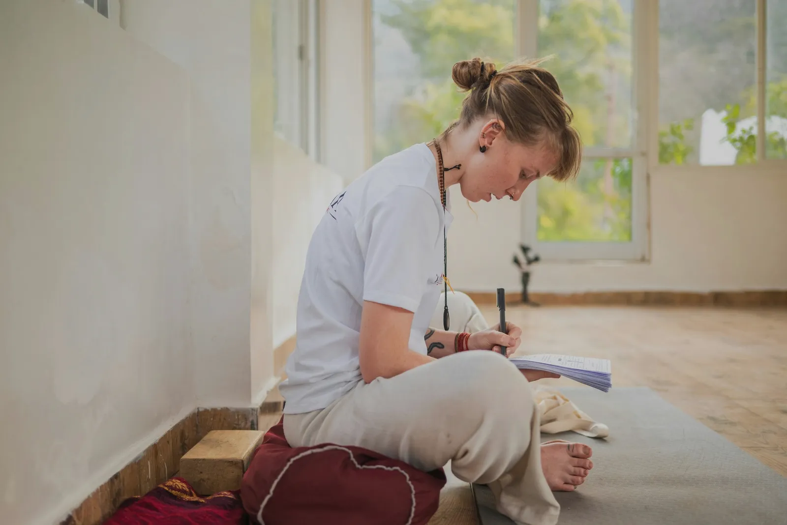 A person writing in a notebook by a window in the morning.