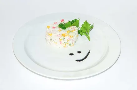 A round salad with herbs on a white plate.