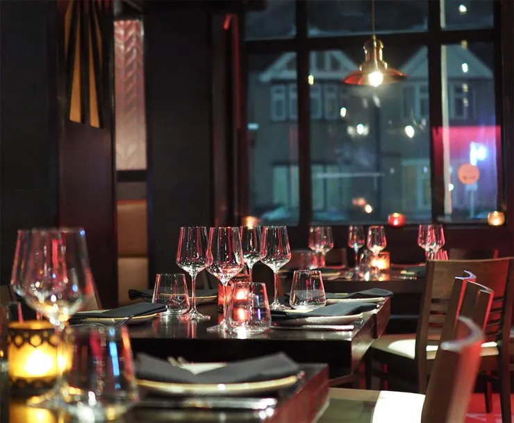 A dim restaurant with set tables and pendant lights.
